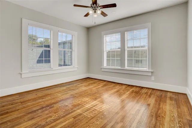 a view of an empty room with a window and wooden floor