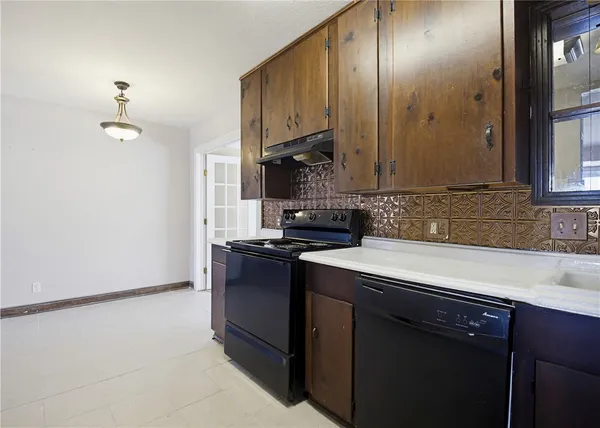 an empty room with wooden floor cabinet and windows