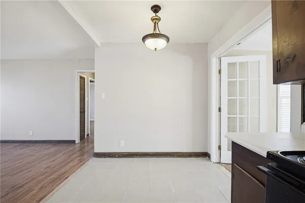 a view of an empty room with window and hardwood floor