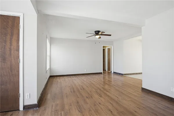 a view of empty room with wooden floor and ceiling fan