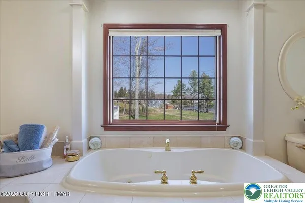 a spacious bathroom with a tub sink and mirror