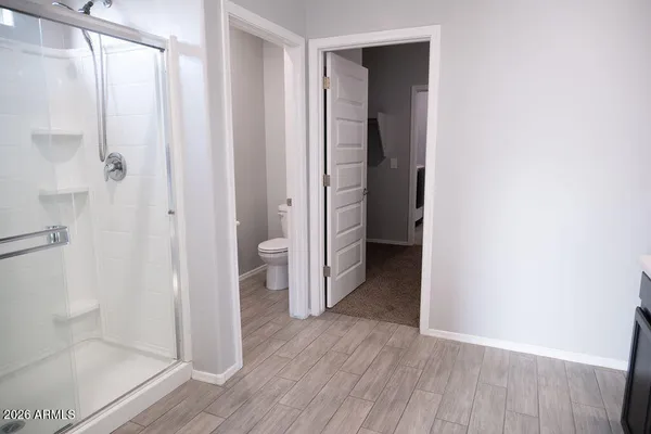 a view of an empty room with wooden floor and a bathroom