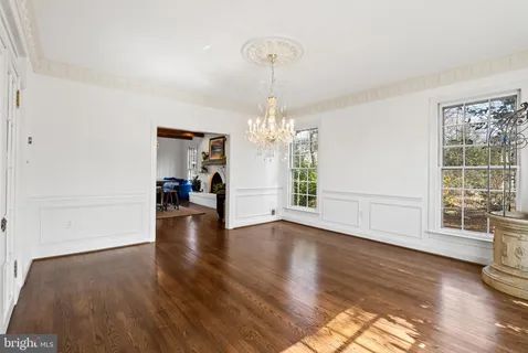 a view of a room with wooden floor chandelier and windows