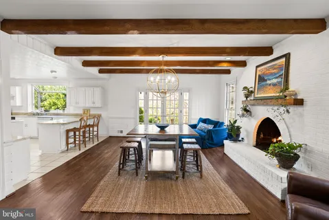 a living room with furniture a fireplace and a dining table with wooden floor