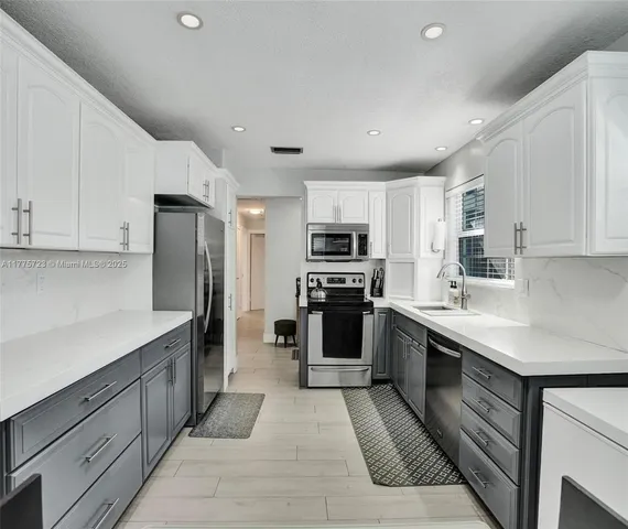 a kitchen with stainless steel appliances kitchen island granite countertop a refrigerator oven a sink dishwasher and white cabinets with wooden floor