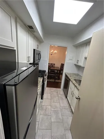a kitchen with granite countertop a refrigerator and a stove top oven