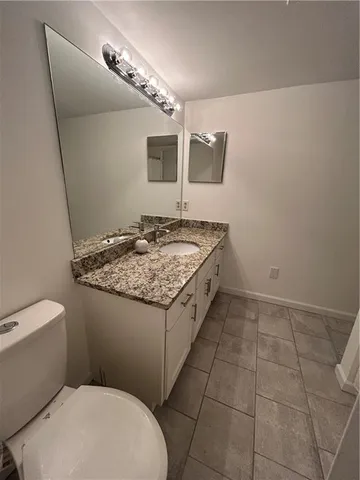 a bathroom with a granite countertop sink a toilet and mirror