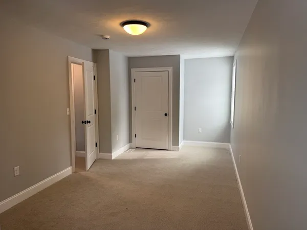 a view of an empty room with closet and a window