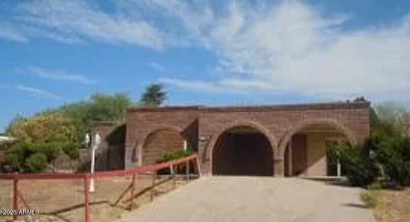 a view of a grey house with large trees