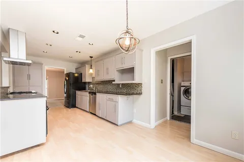 a kitchen with a refrigerator a stove and white cabinets