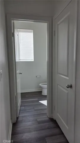 a view of a hallway with wooden floor and a bathroom