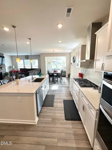 a large white kitchen with stainless steel appliances granite countertop a stove and a sink