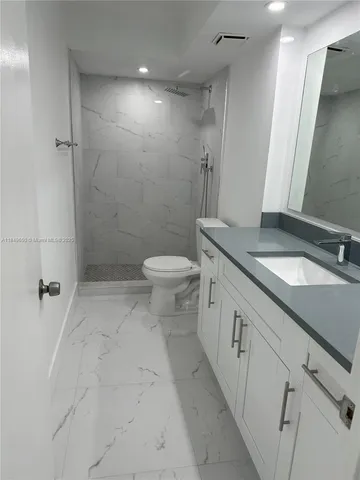a bathroom with a granite countertop sink toilet and shower