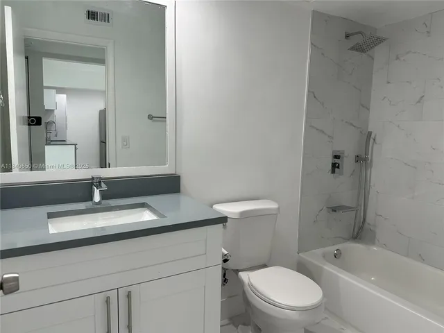 a bathroom with a granite countertop toilet a sink and a bathtub