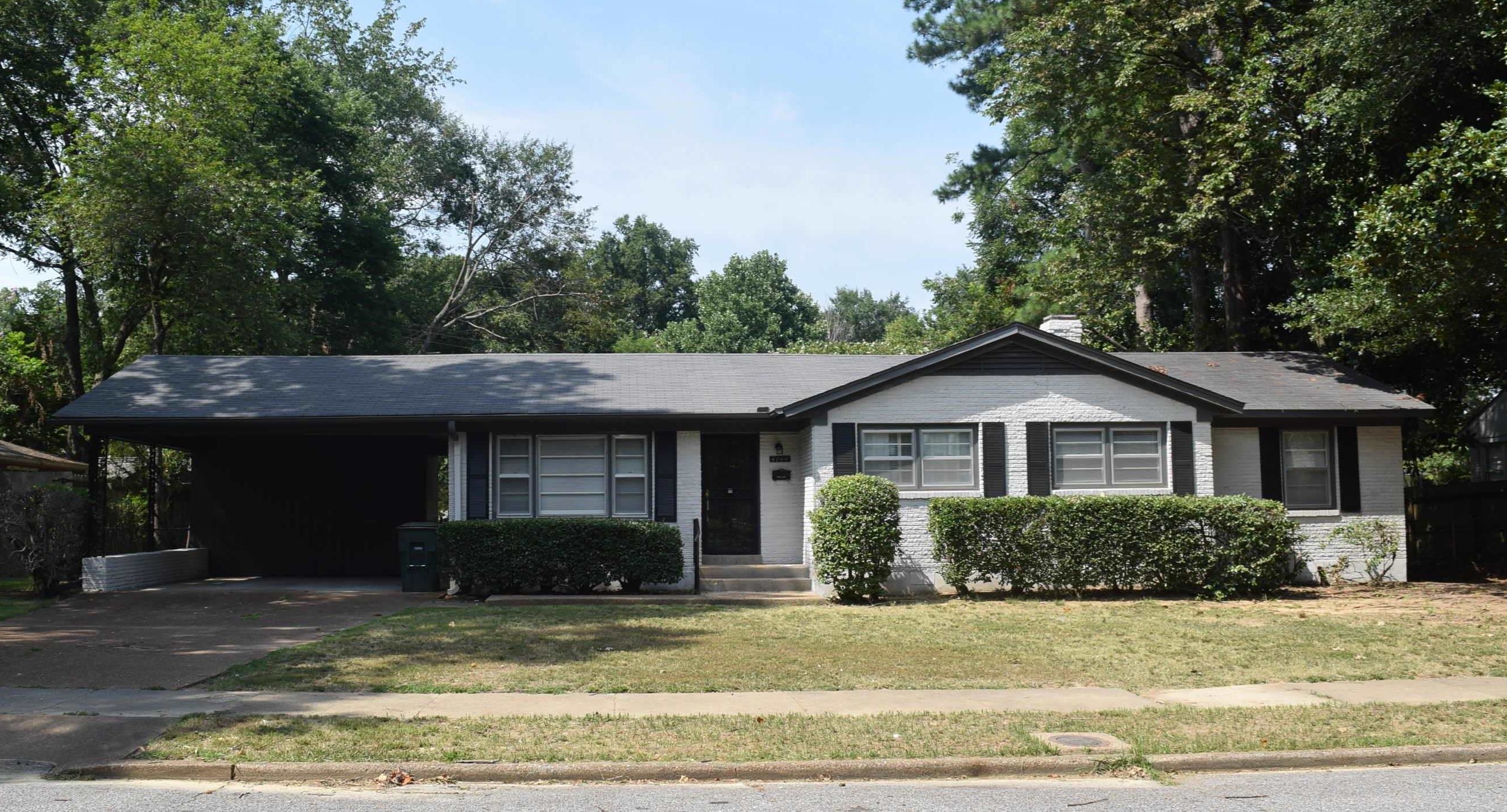 a view of a house with a yard plants and large tree