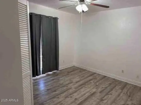 an empty room with wooden floor fan and windows