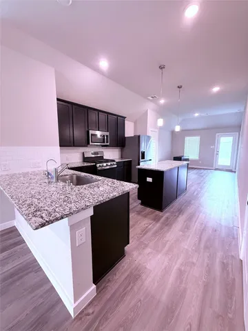 a kitchen with kitchen island a counter top space appliances and a sink