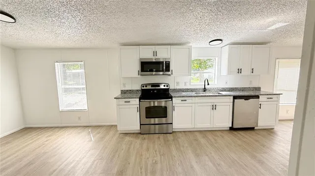 a kitchen with granite countertop white cabinets and white appliances