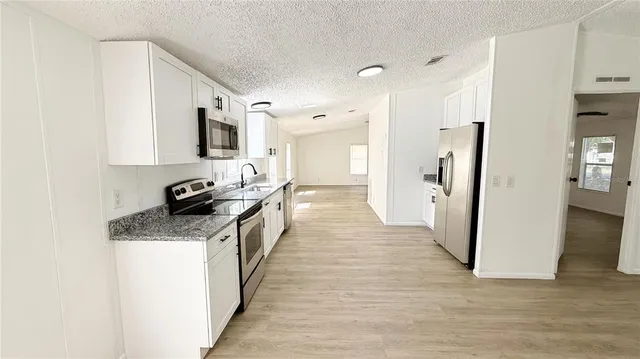 a kitchen with stainless steel appliances granite countertop a refrigerator a stove top oven a sink and dishwasher