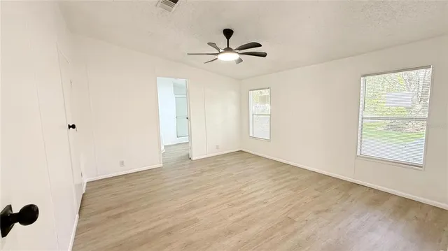 a view of empty room with wooden floor and fan