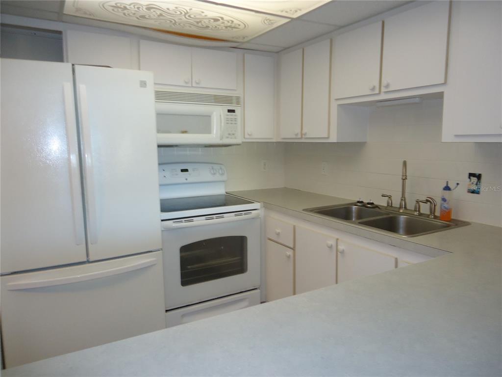 4550 Cove Circle, Unit 405 Madeira Beach, FL 33708 - Photo 4 of 20 a kitchen with white cabinets and white appliances