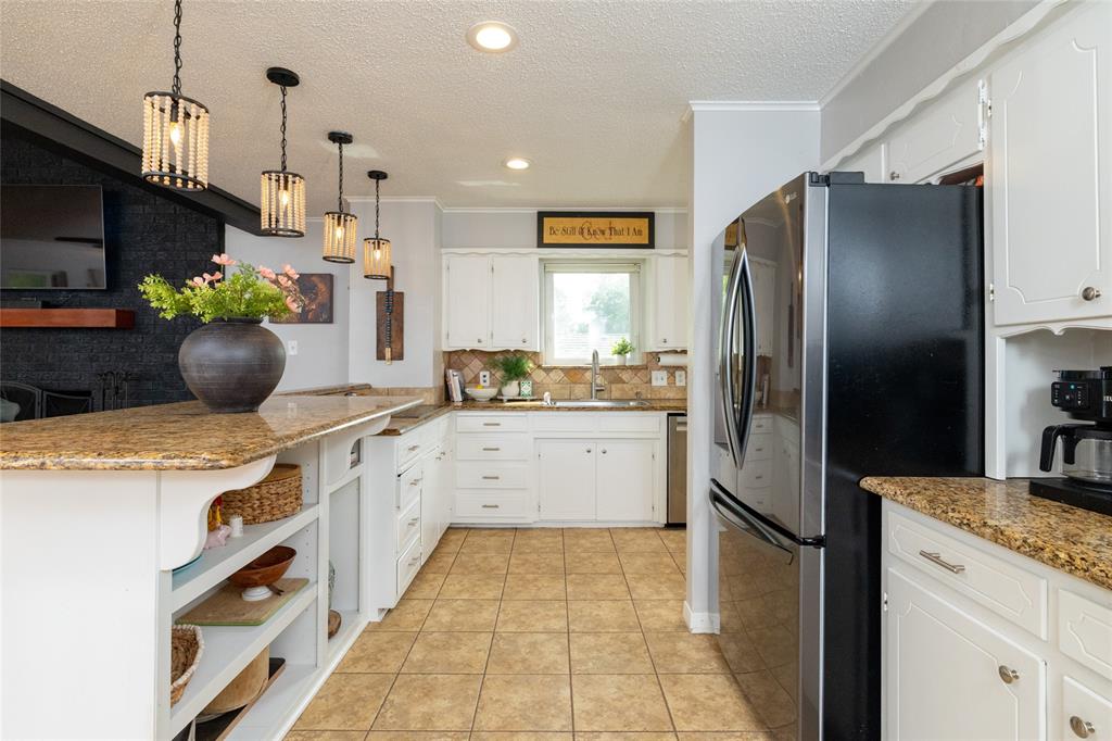 205 Timberlake Drive Azle, TX 76020 - Photo 7 of 40 a kitchen with stainless steel appliances kitchen island granite countertop a refrigerator a sink and a stove