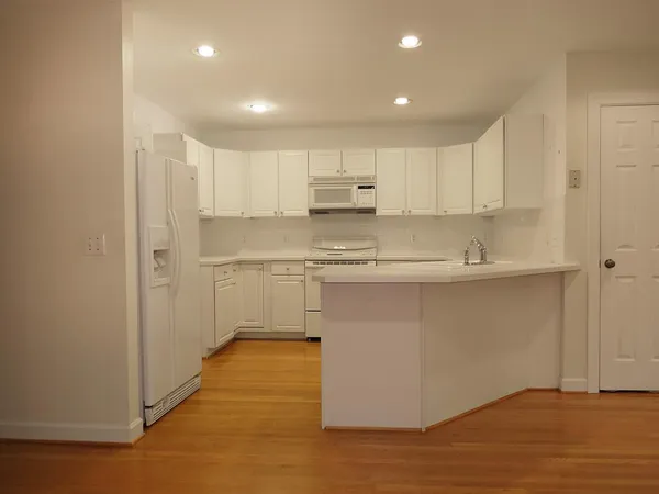 a kitchen with stainless steel appliances granite countertop a sink a stove a refrigerator and white cabinets