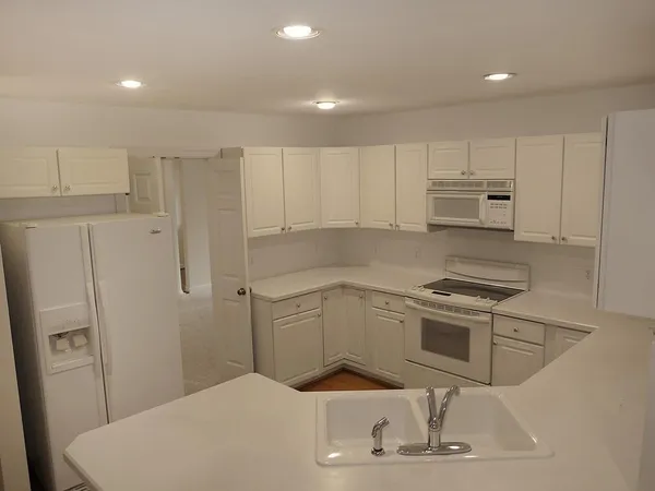 a kitchen with white cabinets and white appliances