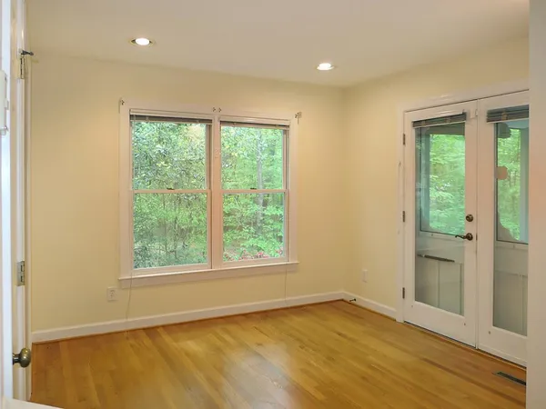 a view of an empty room with wooden floor and a window