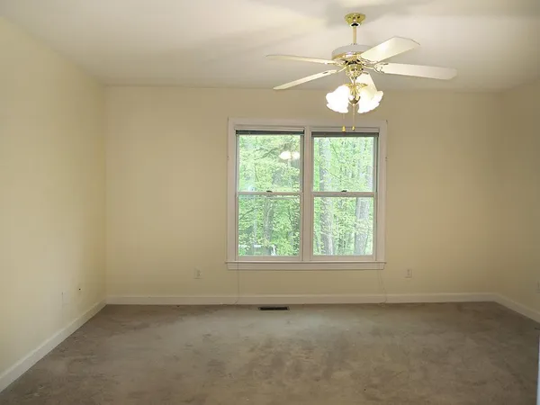 an empty room with a chandelier fan and window