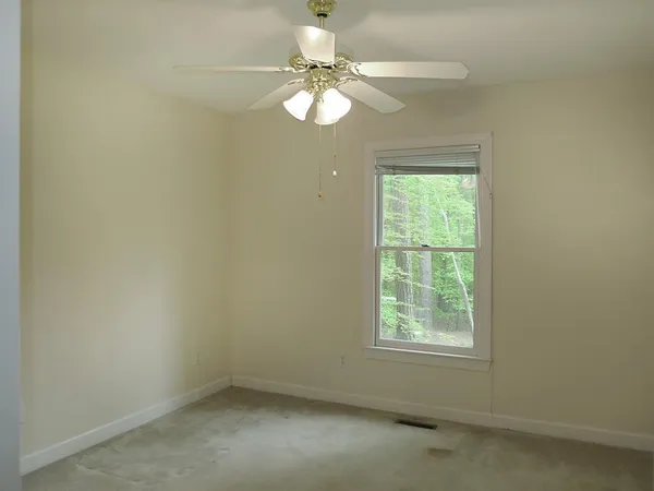an empty room with a window and a chandelier fan