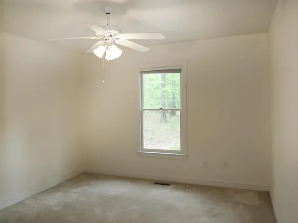 an empty room with a window and a fan