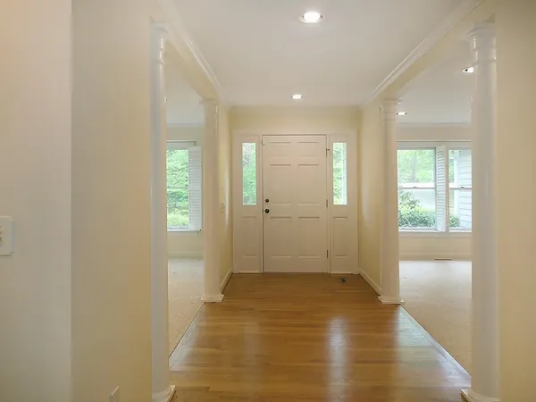 a view of a hallway with wooden floor and a bathroom