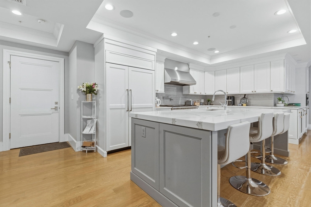 377 West First Street, Unit 5 Boston, MA 02127 - Photo 5 of 27 a kitchen with kitchen island granite countertop a sink cabinets and refrigerator