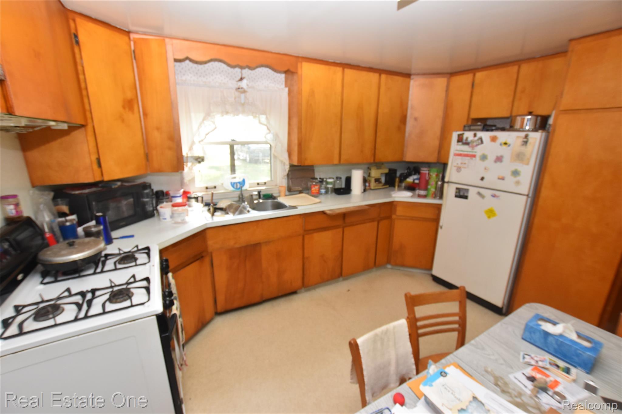 3482 West Maple Road Wixom, MI 48393 - Photo 12 of 17 Kitchen featuring wood-finish cabinetry, white countertops, a stainless steel sink, and a four-burner gas range