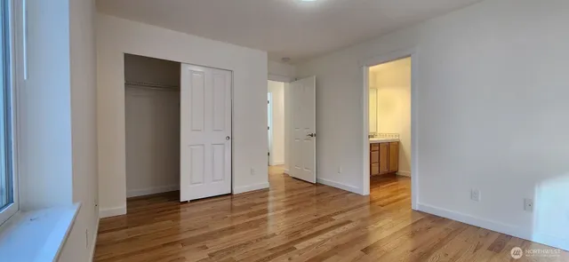 a view of an empty room with wooden floor and closet