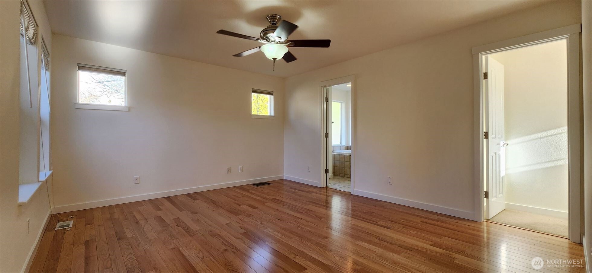 24202 Southeast 21st Street Sammamish, WA 98075 - Photo 22 of 26 an empty room with wooden floor chandelier fan and windows