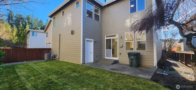 a view of a white house with a small yard and a large tree
