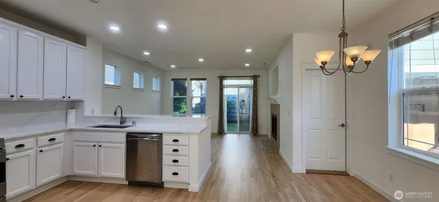 a kitchen with stainless steel appliances granite countertop a sink dishwasher and a refrigerator with wooden floor