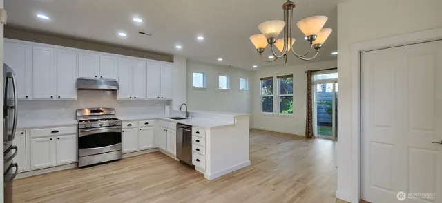 a large kitchen with stainless steel appliances granite countertop a stove and a white cabinets