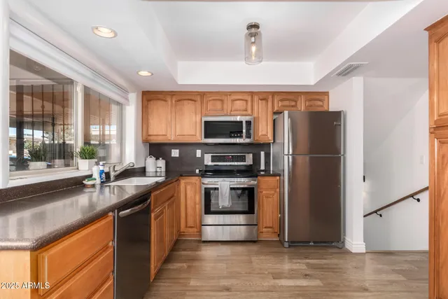 a kitchen with stainless steel appliances granite countertop a refrigerator a stove a sink and a microwave