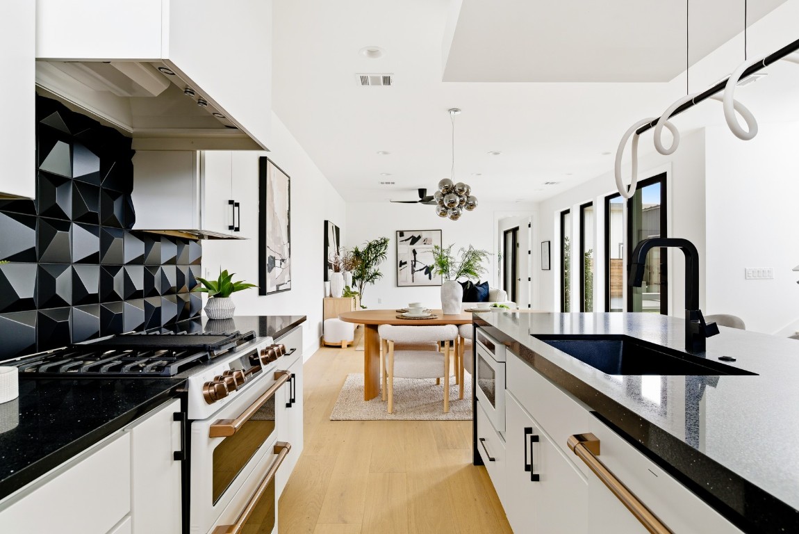 4613 Bolm Road Austin, TX 78702 - Photo 12 of 40 Kitchen featuring dark stone countertops, high end white range, pendant lighting, and white cabinets