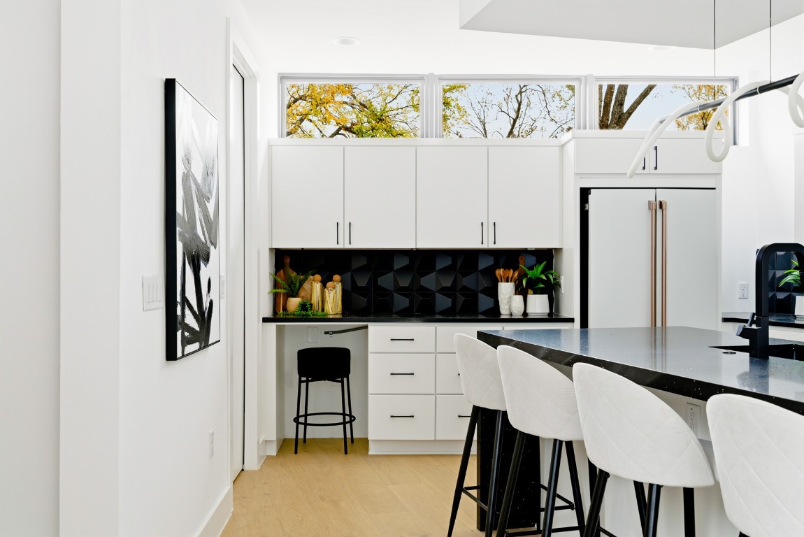 4613 Bolm Road Austin, TX 78702 - Photo 14 of 40 Kitchen with a kitchen bar, decorative backsplash, white cabinetry, and light wood-style flooring