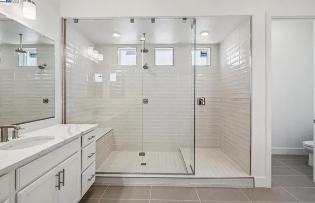 a bathroom with a shower sink vanity and mirror