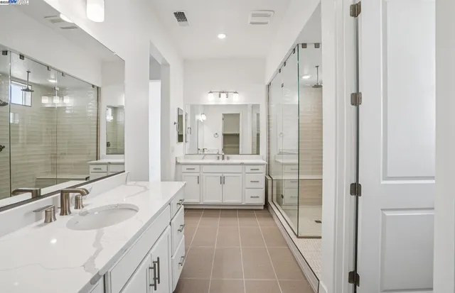 a bathroom with a double vanity sink a toilet a mirror and shower