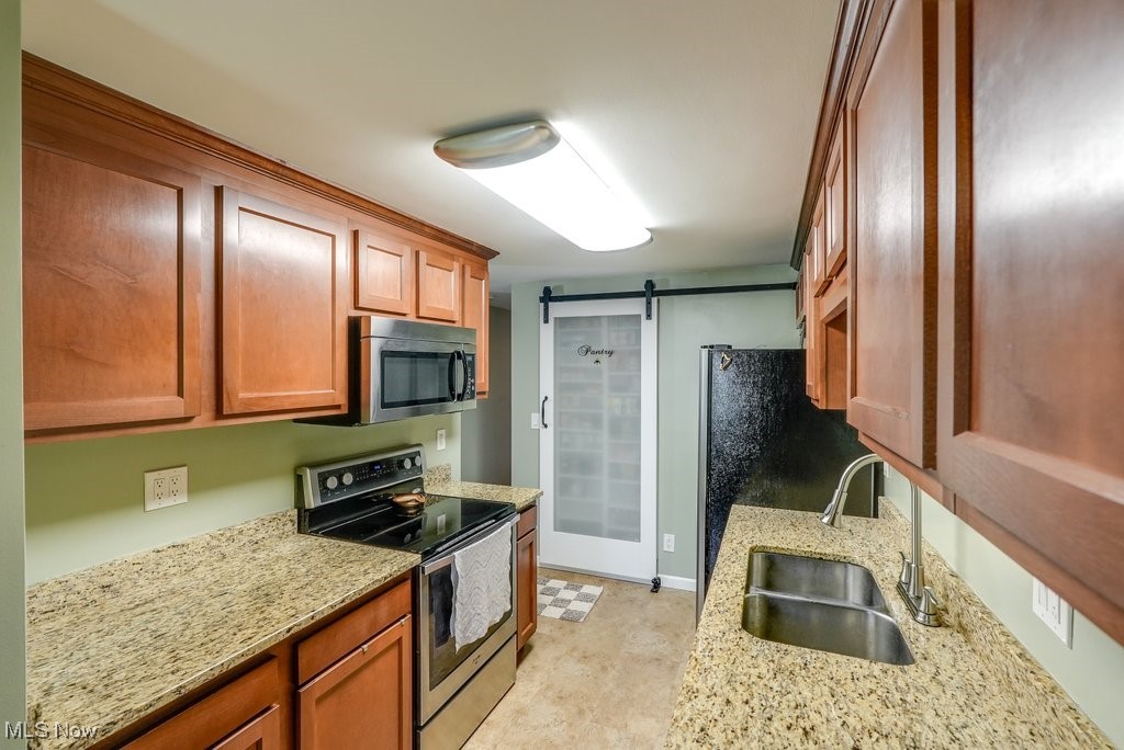 461 New Milford Road Atwater, OH 44201 - Photo 15 of 31 Kitchen with granite countertops, stainless steel appliances, a barn door, and sink