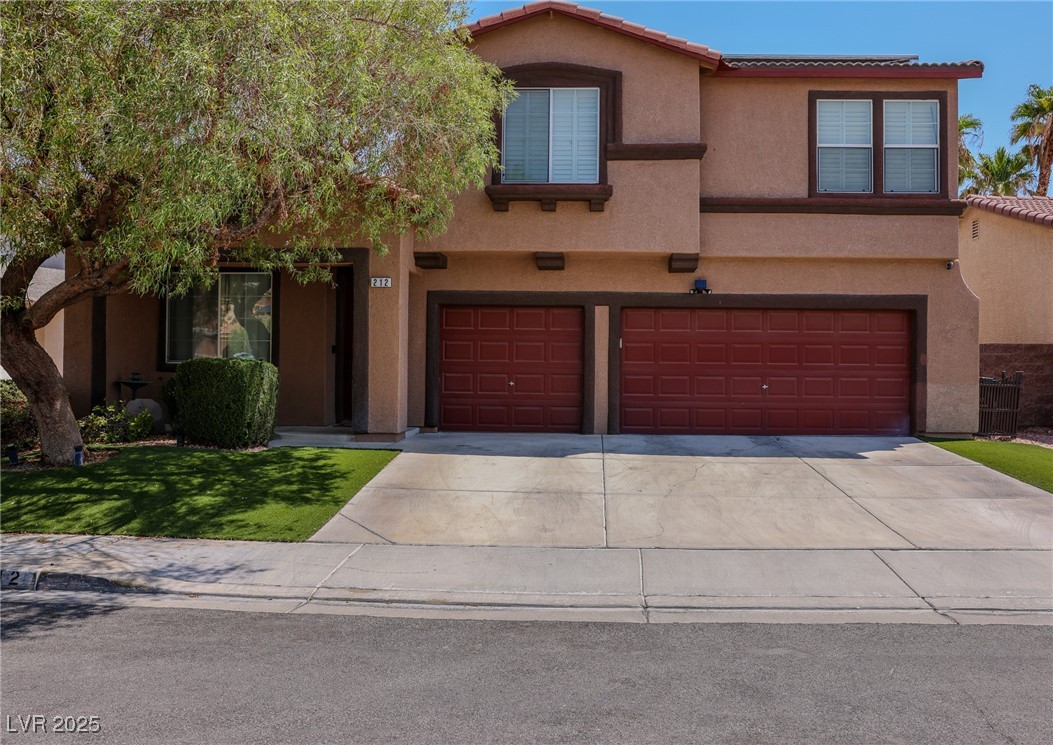 View of front of house featuring an attached garage, stucco siding, concrete driveway, a tiled roof, and a front lawn
