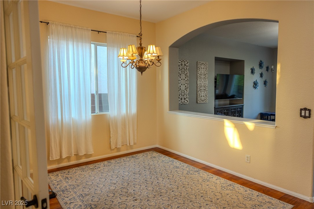 212 Malcolm Street Henderson, NV 89074 - Photo 13 of 47 Unfurnished dining area featuring dark wood-style floors, a chandelier, and arched walkways