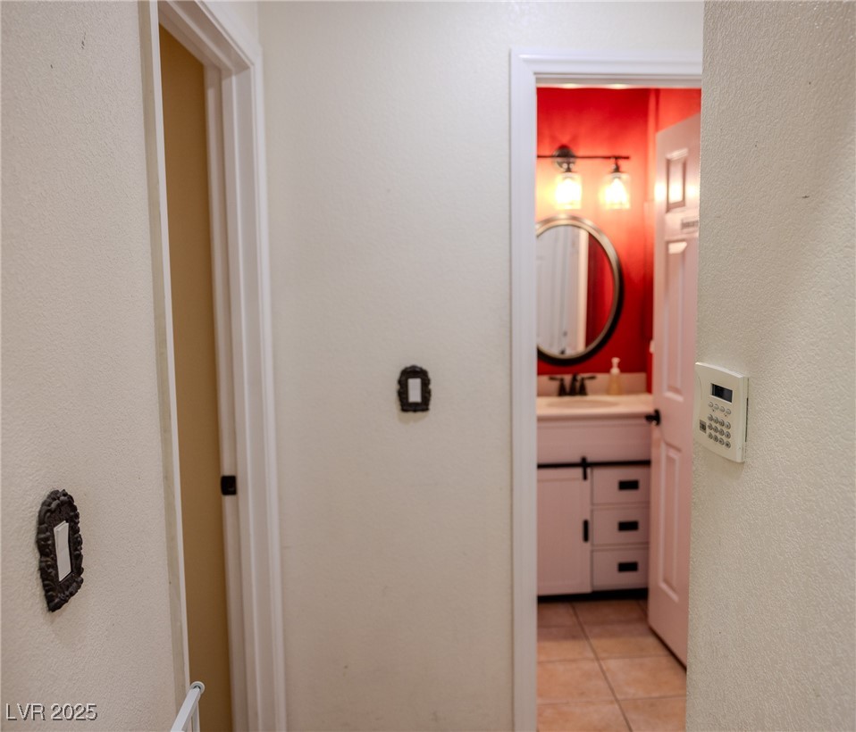212 Malcolm Street Henderson, NV 89074 - Photo 15 of 47 Hallway with a textured wall and light tile patterned floors. Downstairs- guest bedroom 3/4 with shower.