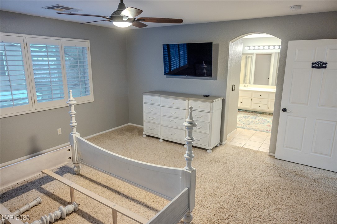 212 Malcolm Street Henderson, NV 89074 - Photo 31 of 47 Bedroom featuring light colored carpet, ceiling fan, and arched walkways